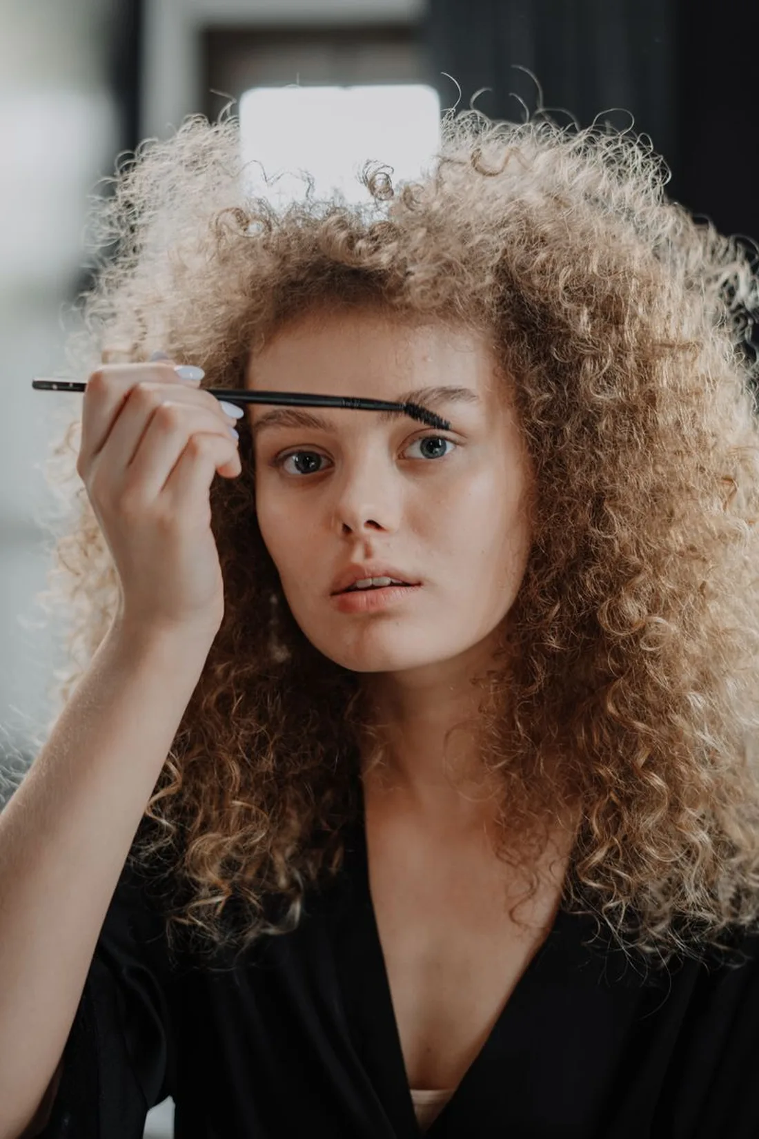 Woman applying strong-hold eyebrow gel with a brush wand