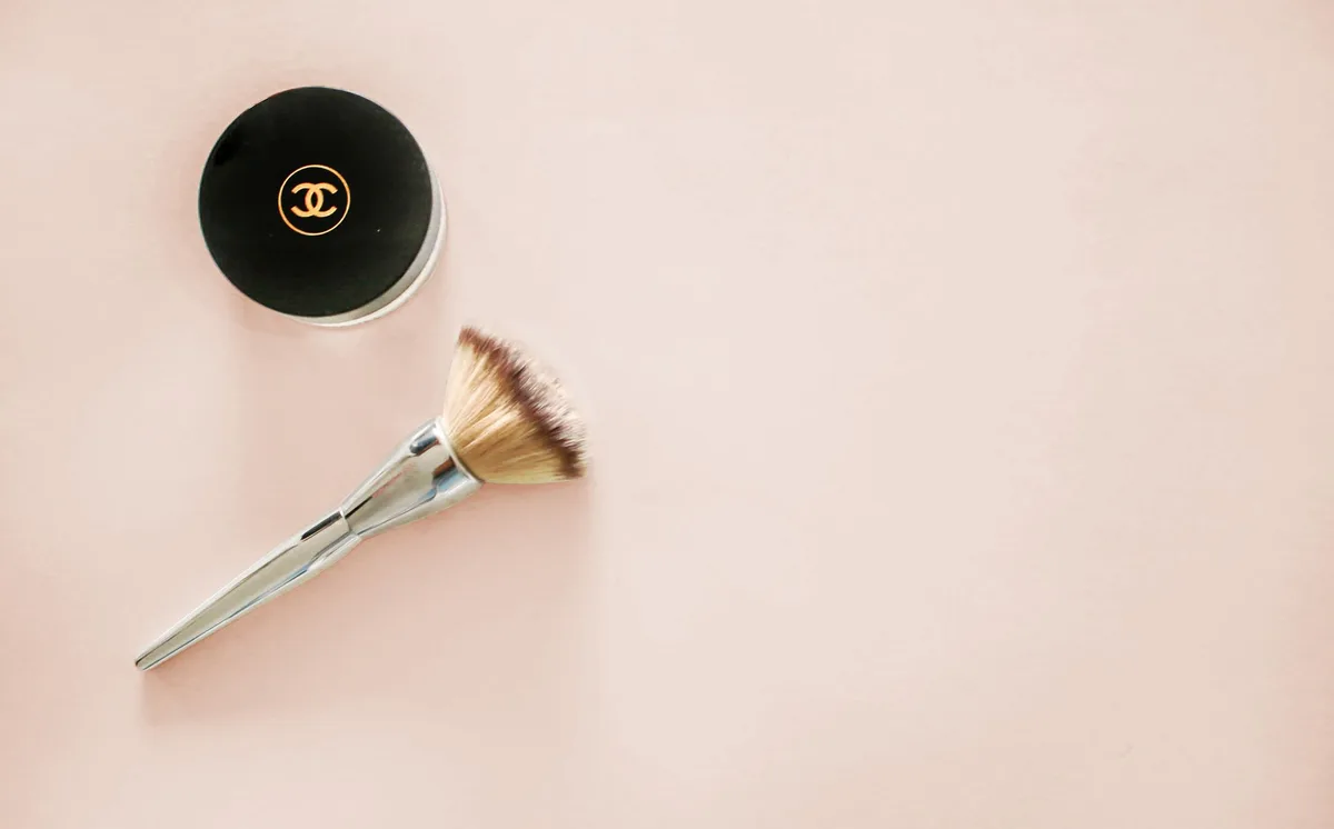 Elegant flat lay of a prestige cosmetics compact and makeup brush