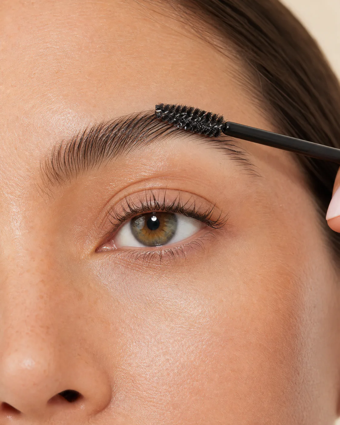 Close-up drugstore brow gel application with a small spoolie