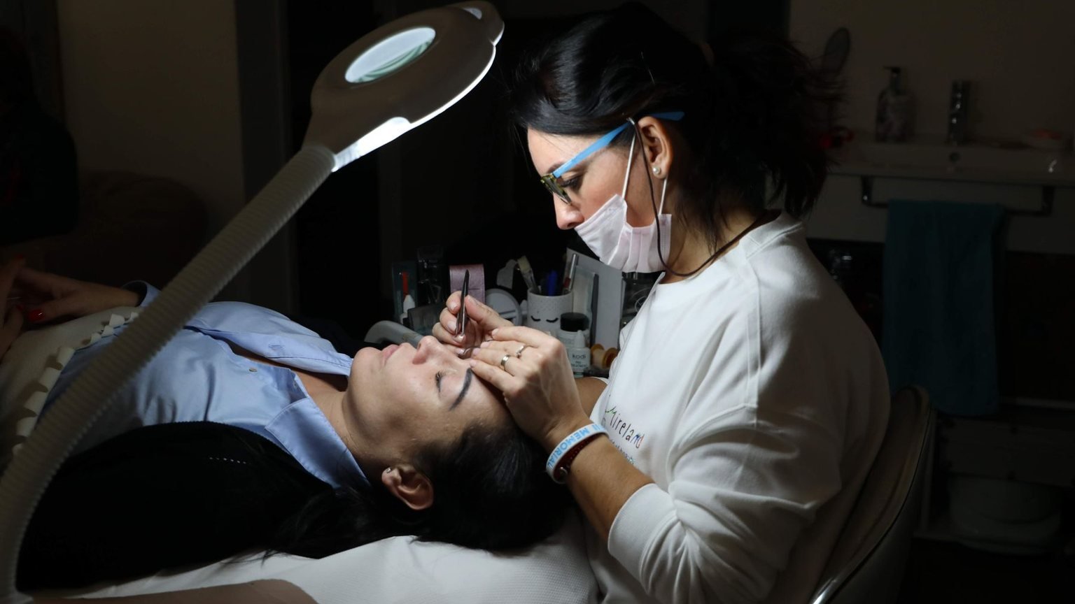 Professional brow stain guide showing a client receiving a precise salon eyebrow treatment