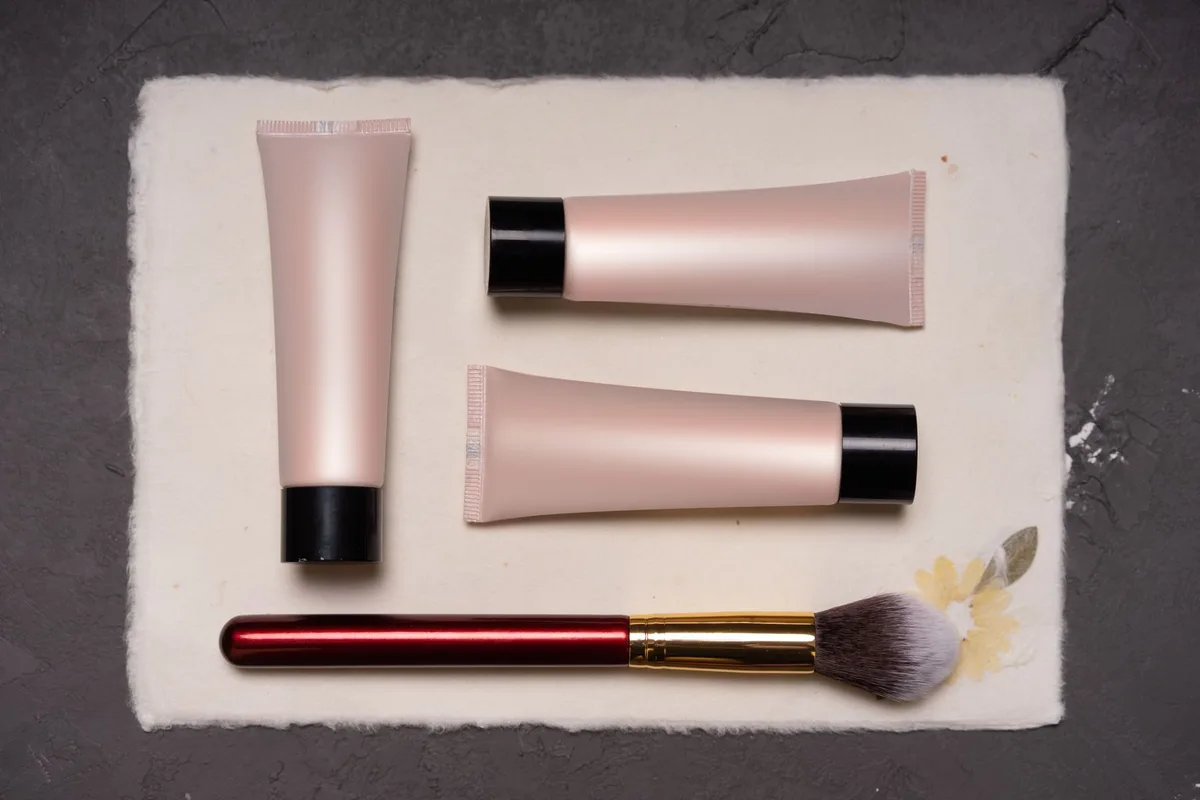 Flat lay of eyebrow gel tubes and a makeup brush