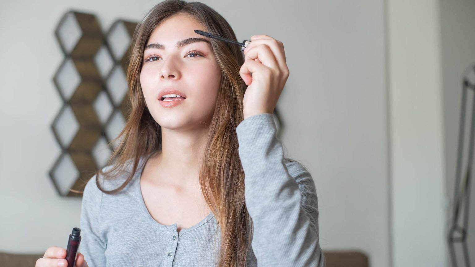 Woman applying the best clear eyebrow gel with a spoolie for natural hold